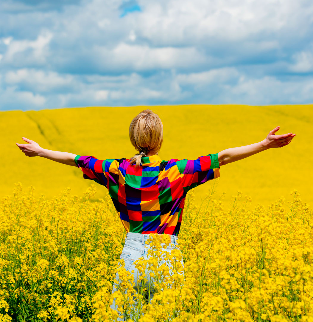 Image d'une femme avec robe jaune dans un champ de tournesols. Sentiment de liberté et de bien-être
