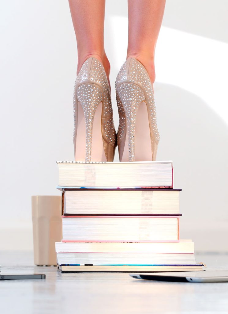 Femme en talons sur une pile de livres. Image symbolisant Pumps, votre espace coaching Rouen : pour s'élever et devenir la personne que vous êtes vraiment